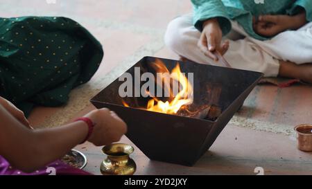 Una famiglia indiana in abbigliamento tradizionale esegue uno Yagya o un Havan, guidato da un prete, per bilanciare le energie nella loro casa. Questo pooja sacro è per armonia Foto Stock