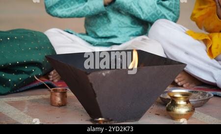 Una famiglia indù si riunisce intorno a un fuoco sacro per Yagya durante una festa. I rituali Havan e pooja includono offerte e mantra vedici Foto Stock