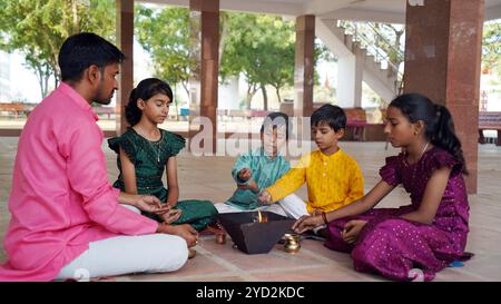 Una famiglia indù si riunisce intorno a un fuoco sacro per Yagya durante una festa. I rituali Havan e pooja includono offerte e mantra vedici Foto Stock