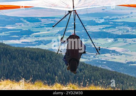 Deltaplano professionista che si decollare dalla cima della montagna. Deltaplano in azione. Volo in volo del pilota deltaplano Foto Stock