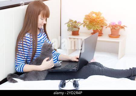 Ragazza incinta con un portatile sul letto. Lavoro remoto . Salute sicurezza . ragazza e lavoro a distanza. Coronavirus. Foto Stock