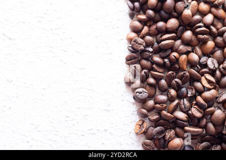 I chicchi di caffè sono sparsi su uno sfondo chiaro . Chicchi di caffè freschi. Concetto di pubblicità di caffè, chicchi di caffè, caffè. Foto Stock