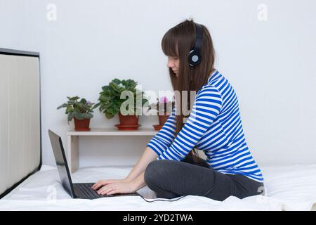 Ragazza incinta con un portatile sul letto. Lavoro remoto . Salute sicurezza . ragazza e lavoro a distanza. Coronavirus. Foto Stock