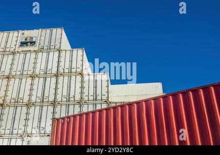 Pila di contenitori di carico refrigerati bianchi contro un cielo azzurro Foto Stock