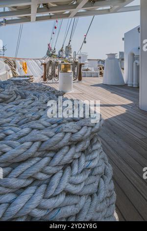 Balikpapan, Indonesia - 24 ottobre 2024. Una grande bobina di spesse corde bianche si trova sul ponte di legno della nave KRI Bima Suci. Le corde sono pulite Foto Stock