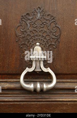 Un porta ornamentali respingente e maniglia su una vecchia porta di legno Foto Stock