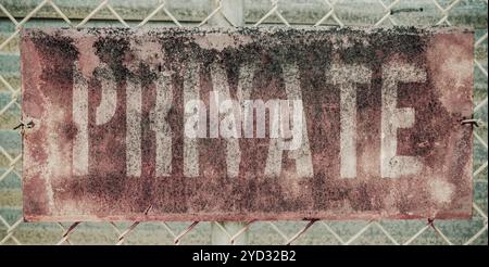 Foto con filtro retro di Rusty Grungy Old Private Property Sign on Chain Link Fence Foto Stock