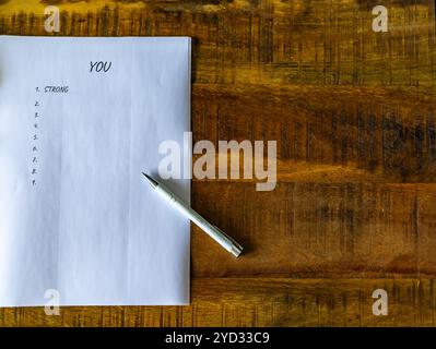 Sopra un foglio di carta c'è una penna che dice "tu". La penna si trova sulla carta al centro della pagina Foto Stock