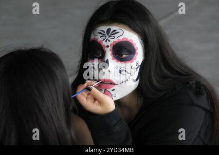 La giovane donna messicana indossa il trucco catrina davanti allo specchio per celebrare la festa del giorno dei morti in Messico Foto Stock