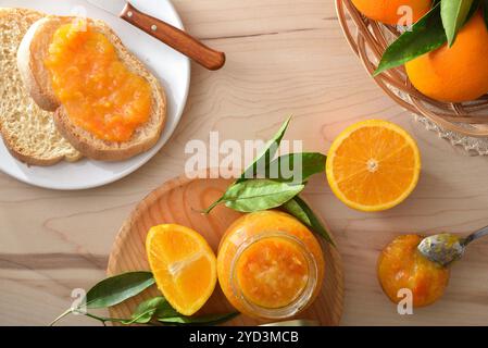 Panca da cucina con colazione preparata con marmellata d'arancia su pane tostato e vasetti e frutta in un cestino. Vista dall'alto. Foto Stock