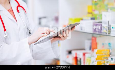 Farmacista che utilizza tablet online che controllano l'inventario delle scorte di farmaci nel settore farmaceutico. Tecnologia per il monitoraggio delle scorte in farmacia con data di scadenza. Foto Stock