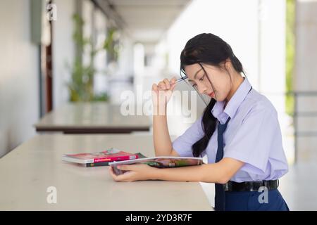 ritratto asiatico scuola uniforme teen ragazza seduta studio compiti. giovane ragazza che impara l'educazione. Foto Stock