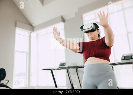 Donna che utilizza il visore VR per un'esperienza di allenamento in una palestra moderna. concetto di fitness, tecnologia e motivazione. Foto Stock