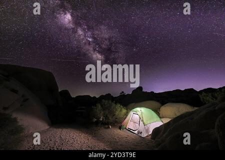 Foto di una tenda illuminata sotto il cielo notturno con le stelle e la via Lattea Foto Stock