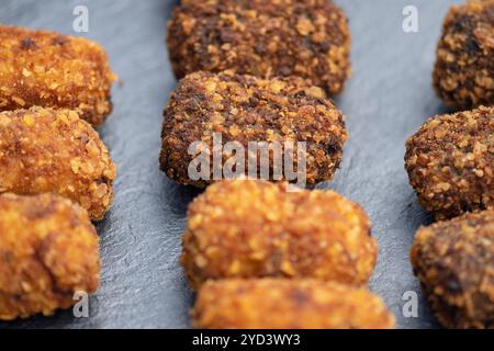 Crocchette spagnole preparate al momento servite su un piatto di ardesia scura, deliziose tapas fritte in profondità, ricoperte di pangrattato con una varietà di ripieni Foto Stock
