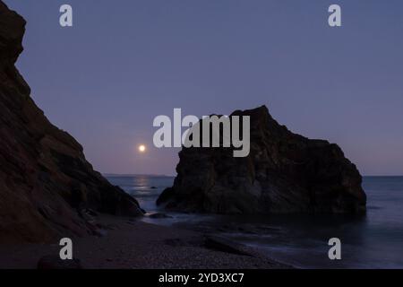 Alba vista attraverso e sopra le rocce alla fine di Plaidy Beach vicino Looe, Cornovaglia, Regno Unito, 17 settembre 2024, notte prima di Super Harvest Moon, Corn Moon Foto Stock