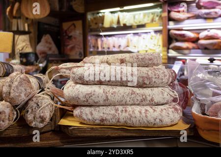 Scaffali impilati con salumi, salumi e salsicce secche e una selezione di formaggi, gustosa esposizione in un negozio artigianale che vende prelibatezze italiane Foto Stock