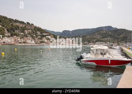 Attraccavano i motoscafi lungo un tranquillo porticciolo, un piccolo villaggio costiero annidato in una collina ricoperta di alberi sotto le aspre montagne Tramuntana, Puerto de Soller Foto Stock