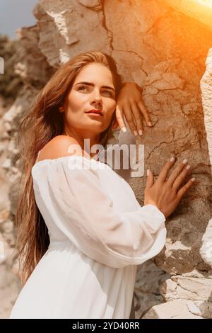 Woman, White Dress, Rock Formation: Una donna con un abito bianco si appoggia contro una scogliera rocciosa. Foto Stock