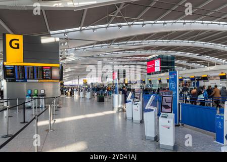 All'interno del Terminal 5, partenze dall'aeroporto Heathrow di Londra, Regno Unito. I passeggeri fanno la fila al check-in per i voli della British Airways. Unità self-service vuote Foto Stock