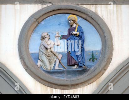 Opere della Misericordia, tondo in terracotta smaltata di Andrea della Robbia, situato tra due archi dell'antico ospedale di San Paolo, in Foto Stock