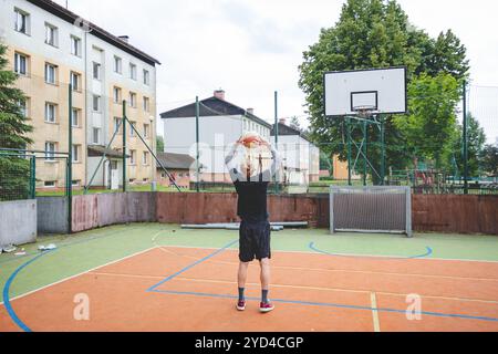 Giocatore di pallavolo che pratica l'impostazione della palla su un campo duro, concentrandosi sul controllo e la precisione durante una sessione di allenamento all'aperto. Una m calma e concentrata Foto Stock