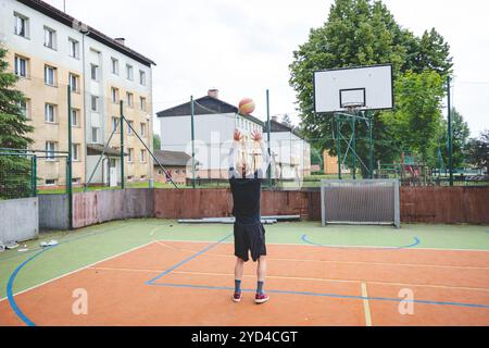 Giocatore di pallavolo che pratica l'impostazione della palla su un campo duro, concentrandosi sul controllo e la precisione durante una sessione di allenamento all'aperto. Una m calma e concentrata Foto Stock