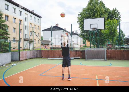 Giocatore di pallavolo che pratica l'impostazione della palla su un campo duro, concentrandosi sul controllo e la precisione durante una sessione di allenamento all'aperto. Una m calma e concentrata Foto Stock