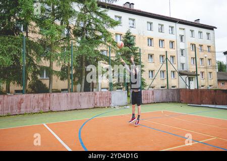 Giocatore di pallavolo che pratica l'impostazione della palla su un campo duro, concentrandosi sul controllo e la precisione durante una sessione di allenamento all'aperto. Una m calma e concentrata Foto Stock