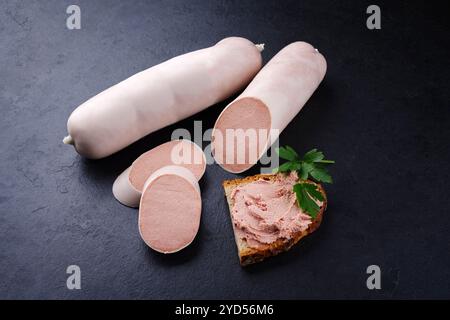 Salsiccia di vitello tradizionale tedesca con pane contadino offerto in primo piano su un piatto nero con spazio di testo Foto Stock