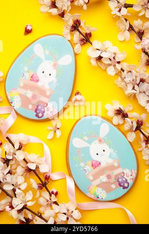Pan di zenzero di Pasqua con fiori di stagione su sfondo giallo. Dolce concetto di Pasqua, biglietto d'auguri. Foto verticale Foto Stock