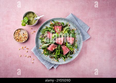 Insalata mista tradizionale con involtini di roast beef ripieni di spinaci e pinoli servita come vista dall'alto su un piatto di design con spazio di testo Foto Stock