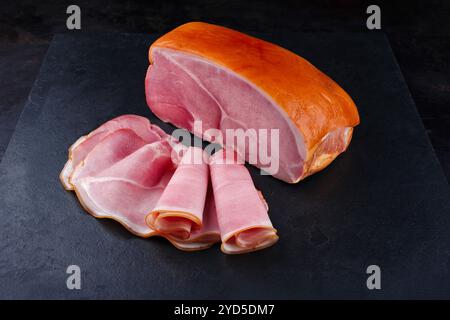 Il tradizionale prosciutto altoatesino tagliato a fette e in un unico pezzo offriva un primo piano su una tavola di design nera con spazio per copiare Foto Stock