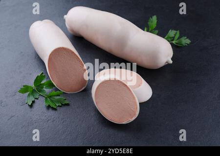 Salsiccia di vitello tradizionale tedesca con pane contadino offerto in primo piano su un piatto nero con spazio di testo Foto Stock