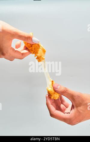 I bastoncini di mozzarella impanata e croccanti di formaggio si allungano a due mani Foto Stock