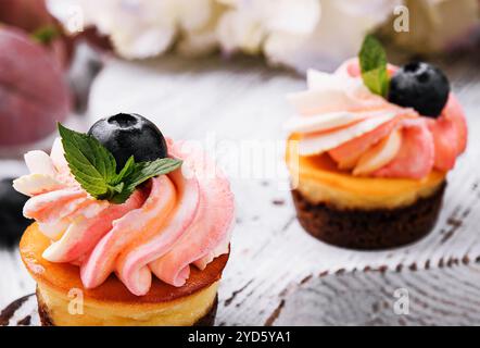 Cupcake al cioccolato con panna rosa e mirtillo fresco Foto Stock