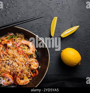 Mescolare gli spaghetti con verdure e gamberetti nel recipiente nero Foto Stock