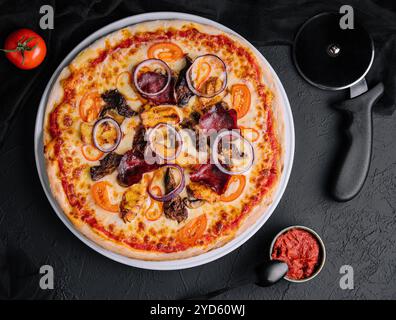 Pizza sul tagliere con taglierina nelle vicinanze, vista dall'alto Foto Stock