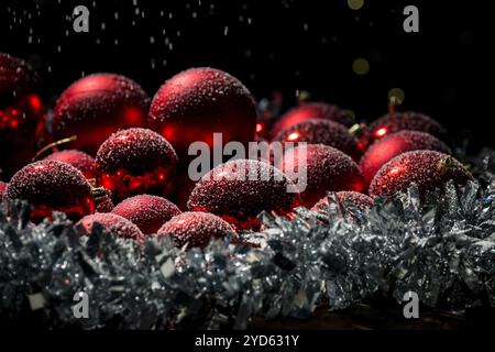 Decorazioni degli alberi di Natale e Capodanno: Decorazioni rosse ricoperte di fiocchi di neve, splendide nevicate animate, foto ravvicinata. Foto Stock