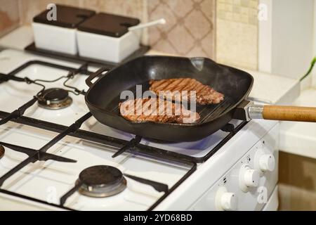 Il processo di cottura di due bistecche di manzo in padella, le mani dello chef maschile che salina carne cruda, primo piano Foto Stock