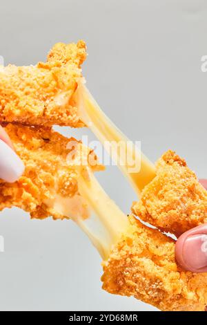 I bastoncini di mozzarella impanata e croccanti di formaggio si allungano a due mani Foto Stock