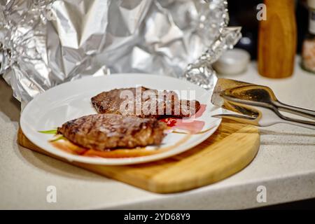 Bistecca alla griglia appoggiata sotto un foglio di alluminio prima di servire Foto Stock