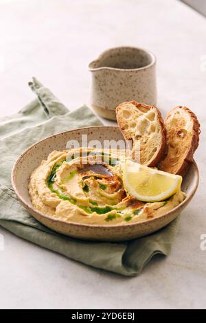 Delizioso hummus fatto in casa con limone, paprika, olio d'oliva e microverdure. Piatto vegetariano mediorientale Foto Stock