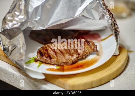 Bistecca alla griglia appoggiata sotto un foglio di alluminio prima di servire Foto Stock