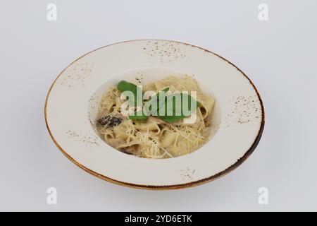 Fettuccine con salsa panna, pollo e funghi in un piatto bianco su sfondo bianco. Foto Stock