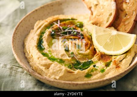 Delizioso hummus fatto in casa con limone, paprika, olio d'oliva e microverdure. Piatto vegetariano mediorientale Foto Stock