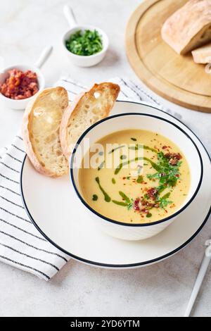 Ciotola di zuppa di patate con prezzemolo e pancetta con crostini di pane tostato in ciotola bianca. Pasto confortevole Foto Stock