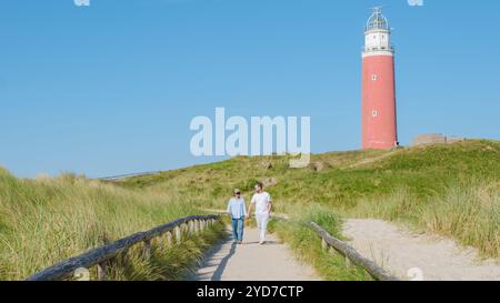 Un uomo e una donna passeggiano piacevolmente lungo un sentiero tortuoso vicino all'iconico faro di Texel, godendosi la vista panoramica del Foto Stock