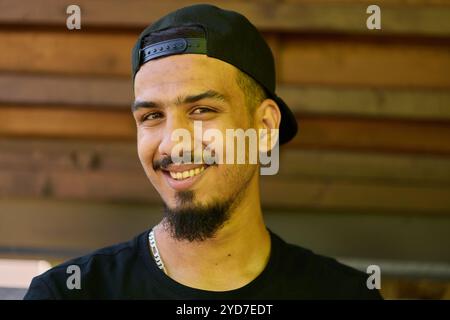 Un sorprendente primo piano che cattura il sorriso radioso di un adolescente sudanese, completato da un mento e da un berretto elegante. Foto Stock