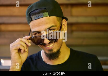 Un sorprendente primo piano che cattura il sorriso radioso di un adolescente sudanese, completato da un mento e da un berretto elegante. Foto Stock